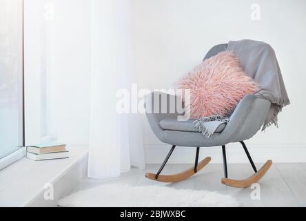 Oreiller et plaid moelleux sur fauteuil dans la chambre Banque D'Images