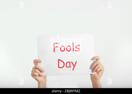 Femme tenant une feuille de papier avec l'expression « Fools day » sur fond blanc. Célébration du 1 avril Banque D'Images