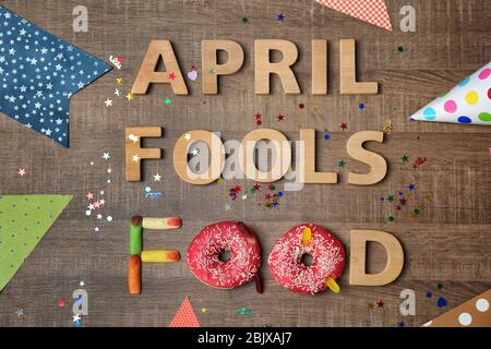 Composition avec phrase 'avril fools food', beignets et bonbons de gelée sur fond de bois Banque D'Images