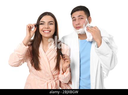 Jeune homme avec mousse à raser et sa petite amie appliquant du mascara sur fond blanc Banque D'Images