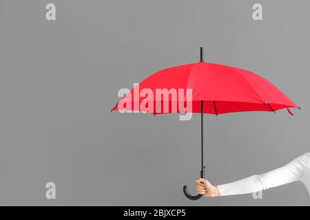 Femme portant un élégant parapluie rouge sur fond gris Banque D'Images