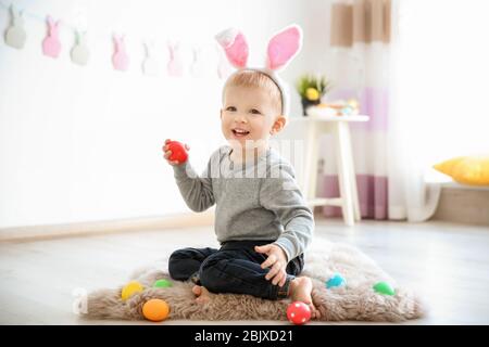 Joli petit garçon avec des oreilles de lapin tenant l'oeuf de Pâques à l'intérieur Banque D'Images