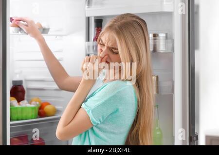 Jeune femme se sentir mauvaise odeur du réfrigérateur dans la cuisine Banque D'Images
