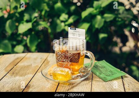 Gros plan de thé dans une tasse de verre avec du thé, du miel, du cookie, du sucre. Fond rustique en bois de table ronde. Plein soleil. Style de vie. Citation de vie. Banque D'Images