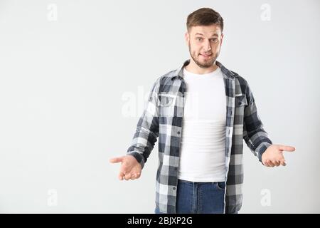 Jeune homme confus sur fond clair Banque D'Images