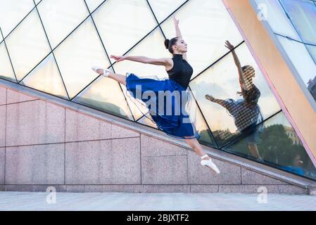 belle jeune danseuse de la ville vêtue de vêtements de danse est dansant en mouvement et sautant Banque D'Images