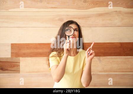 Jeune femme avec une loupe sur fond de bois Banque D'Images