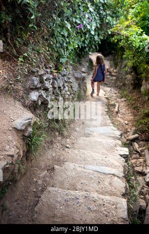 Le touriste féminin descend long passage de marches en béton sur le célèbre sentier de randonnée côtier en direction de Monterosso du village de Vernazza, Cinque Terre; I Banque D'Images