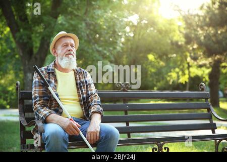 Blind Man sitting on bench in park Banque D'Images