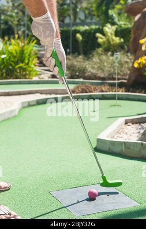 Homme en train de se teindre au mini-golf en portant des gants de protection Banque D'Images