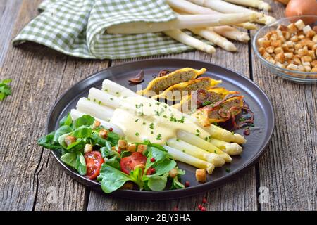 Asperges blanches avec raviolis de viande farcis frits de style swabian servis avec salade de maïs avec croûtons Banque D'Images