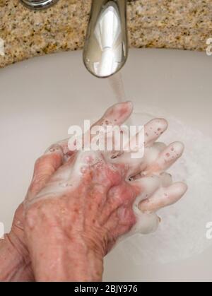 Femme âgée se lavant les mains dans le lavabo de la salle de bains, gros plan des mains Banque D'Images