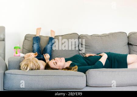 Femme enceinte couchée sur un canapé avec son fils (4-5) Banque D'Images