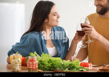 Jeune couple boire du vin tout en faisant cuire ensemble dans la cuisine Banque D'Images