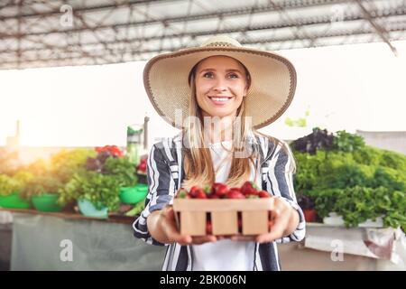 Femme avec des fraises fraîches dans panier at market Banque D'Images