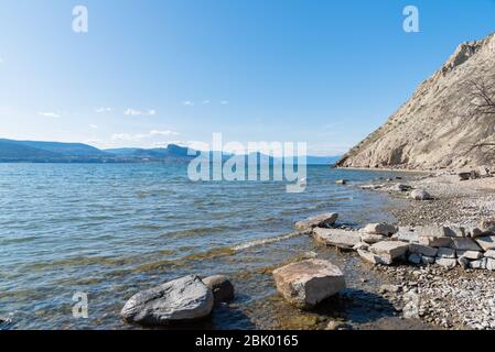 Littoral rocheux et falaises de grès sur le lac Okanagan avec vue sur le ciel bleu et les montagnes Banque D'Images