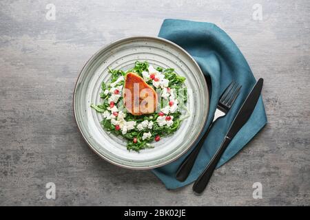 Plaque avec salade savoureuse et de poire sur fond gris Banque D'Images