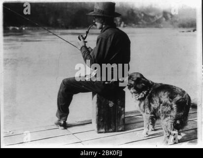 Hooch Hound, un chien formé pour détecter la liqueur (comme suggéré au commissaire Haynes par un agent d'interdiction au Colorado), des escargots dans le ballon dans la poche arrière de l'homme, assis, pêcher sur la jetée sur le Banque D'Images