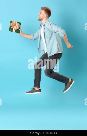 Happy Young man with gift box sur un fond de couleur Banque D'Images