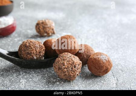 Spoon avec de délicieuses truffes douces sur fond gris Banque D'Images