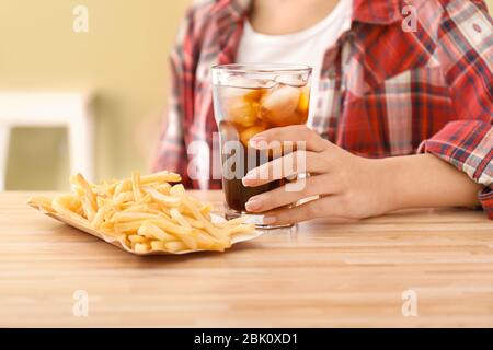 Femme avec verre de cola froid et frites à table Banque D'Images