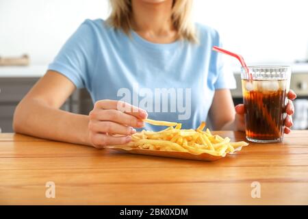 Femme avec verre de cola froid et frites à table Banque D'Images