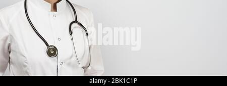 Vue rognée d'un médecin de sexe féminin posant avec un stéthoscope en uniforme. Travailleur du système de santé en gants blancs et chirurgicaux. Médecine, Santé Banque D'Images