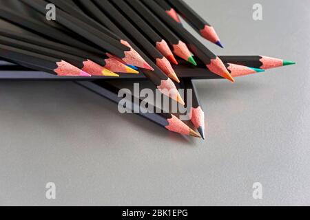 Gros plan d'un groupe de crayons de couleur noire sur un fond gris métallisé avec espace de copie. Concept de diversité et de créativité. Banque D'Images