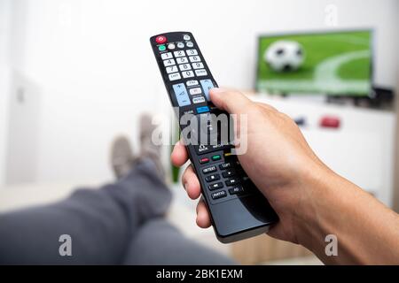 Regarder la télévision. La télécommande en main. Regarder le football à la télévision. L'homme allongé sur le canapé en regardant la télé Banque D'Images
