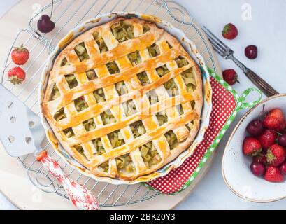 Tarte au rhubarbe maison sur le rack de refroidissement. Décoration aux baies fraîches d'été. Vue de dessus. Banque D'Images