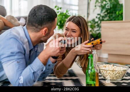 Heureux couple se posant sur le sol et jouant aux jeux vidéo.couple Jeune jouant aux jeux vidéo dans leur appartement.Hobbies et concept de loisirs. Banque D'Images