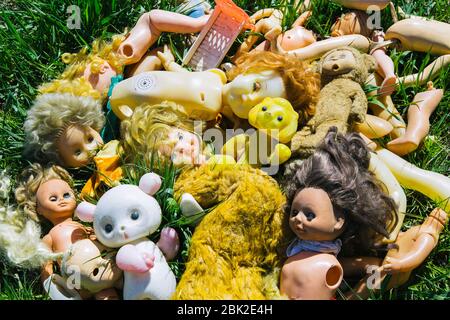 Beaucoup de vieilles poupées et jouets cassés sur l'herbe projetée comme une poubelle Banque D'Images