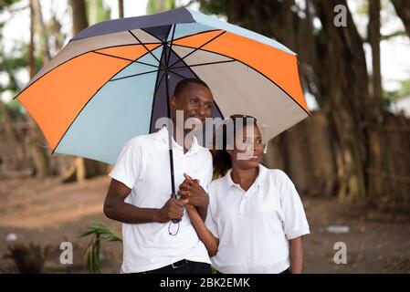 couple touristique romantique debout devant tenant les mains sous un parapluie coloré Banque D'Images