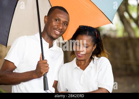 couple touristique romantique debout devant tenant les mains sous un parapluie coloré Banque D'Images
