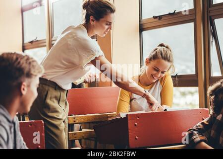 Professeur de femme aidant un étudiant en classe pendant la conférence. Professeur de femme aidant une fille étudiante pendant une classe au lycée. Banque D'Images