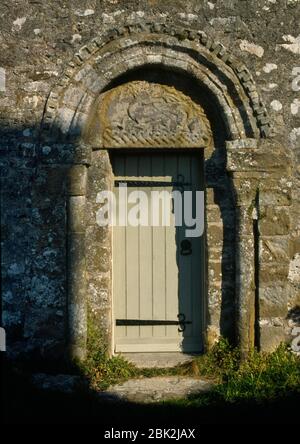 Porte du C12ème S à la nef de l'église St Seiriol, Prieuré de Penmon, Anglesey, Pays de Galles, Royaume-Uni. Tympan sculpté avec un bec de rouching qui morne sa queue. Banque D'Images