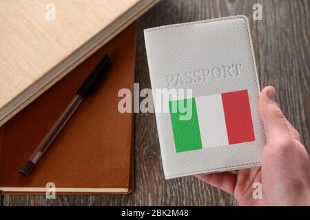 Main tenant un passeport italien. Livres en arrière-plan Banque D'Images