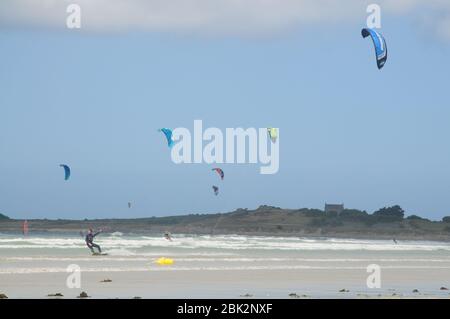 Les planches à voile et les kitesurf profitent de conditions venteuses sur une plage près de Santec, dans le nord de la Bretagne, en France. Banque D'Images