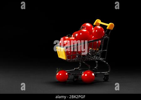 Mini panier avec tomates cerises sur fond noir. Alimentation saine et nourriture végétarienne, concept de cuisine. Foyer sélectif. Espace de copie Banque D'Images