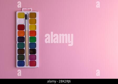 Palette rectangulaire de boîtes avec aquarelles de couleur miel et pinceau sur fond rose , copier spase Banque D'Images