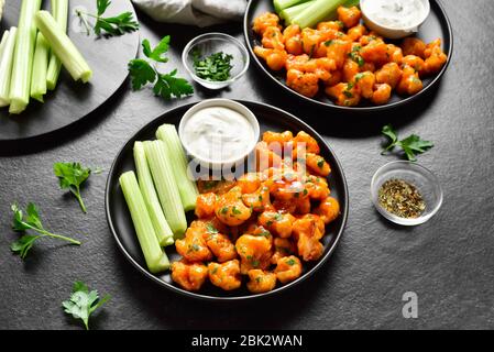Ailes de buffle de chou-fleur avec céleri et sauce sur plaque sur fond de pierre noire. Alimentation saine, concept de nourriture à base de plantes. Banque D'Images