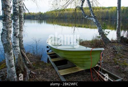 Barque verte en fibre de verre amarrée au bord du lac , Finlande Banque D'Images
