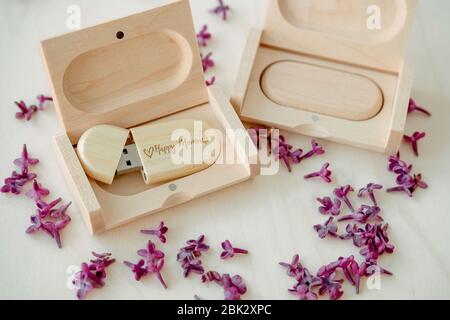 Clés USB marron en bois avec boîtes contenant le texte Happy moments avec pétales lilas sur fond blanc, stockage de données, belle rétroaction à clié Banque D'Images