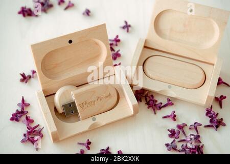 Clés USB marron en bois avec boîtes contenant le texte Happy moments avec pétales lilas sur fond blanc, stockage de données, belle rétroaction à clié Banque D'Images