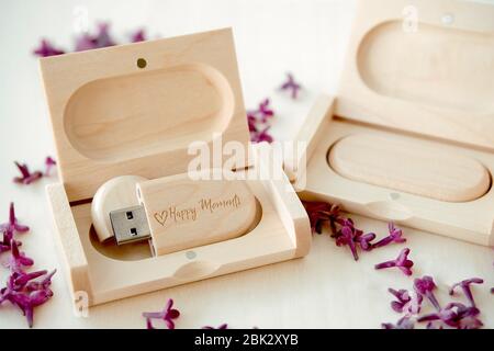 Clés USB marron en bois avec boîtes contenant le texte Happy moments avec pétales lilas sur fond blanc, stockage de données, belle rétroaction à clié Banque D'Images