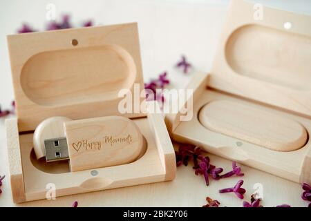 Clés USB marron en bois avec boîtes contenant le texte Happy moments avec pétales lilas sur fond blanc, stockage de données, belle rétroaction à clié Banque D'Images