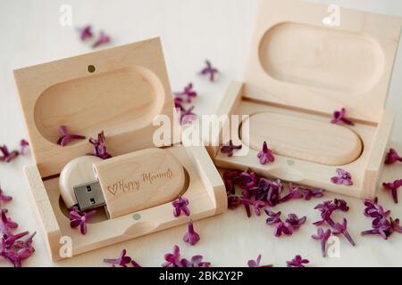 Clés USB marron en bois avec boîtes contenant le texte Happy moments avec pétales lilas sur fond blanc, stockage de données, belle rétroaction à clié Banque D'Images