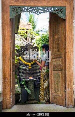 Femme priant devant une statue de Ganesh, Ubud, Bali, Indonésie Banque D'Images