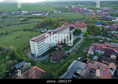 Hôpital de la ville de Huedin-(Spitalul orasenesc Huedin) photo aérienne, vue d'en haut. Maisons tziganes en arrière-plan. Banque D'Images