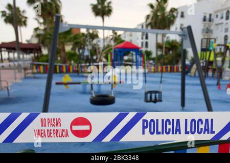 La police espagnole ferme une aire de jeux pour enfants en faisant le cordon de la cour de jeux avec des bandes de cordon de police. Banque D'Images